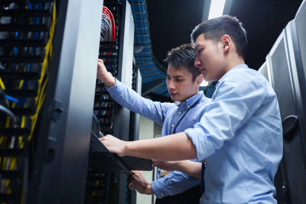 Young IT engineers inspecting data center servers. Young IT engineers inspecting data center servers.